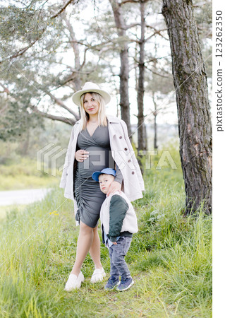 Pregnant mother and her little son walking in the forest and spending time together. Pregnant mother and her little son walking in the forest and spending time together. 123262350
