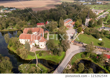 Aerial View of a Castle Surrounded by Water and Trees in Jaunpils, Latvia Aerial View of a Castle Surrounded by Water and Trees in Jaunpils, Latvia 123262544