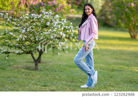 Woman in pink jacket standing in park. Shallow depth of feld 123262986