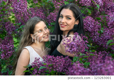 Woman and sister posing in lilac garden. Shallow depth of feld 123263001