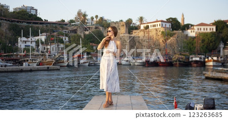 Elegant woman posing at sunset by the harbor  123263685