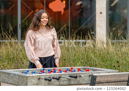 Woman Enjoys Playing Foosball Outdoors at a Casual Gathering in the Park 123264082