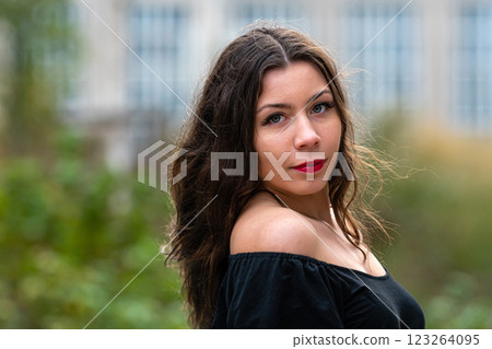 Young Woman With Long Hair Wearing Off-Shoulder Top Posing Outdoors in Urban Setting Young Woman With Long Hair Wearing Off-Shoulder Top Posing Outdoors in Urban Setting 123264095