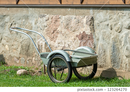 a two-wheeled metal wheelbarrow for transporting goods in the yard of a rural farm a two-wheeled metal wheelbarrow for transporting goods in the yard of a rural farm 123264270
