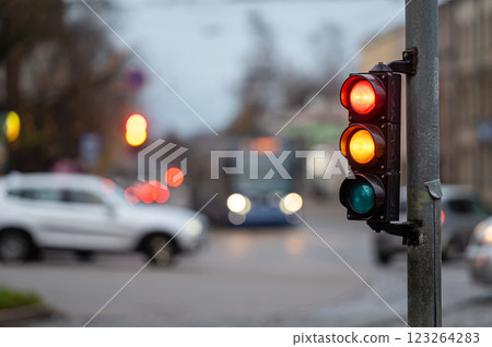 view of city traffic with traffic lights, in the foreground a semaphore with a red and orange light 123264283