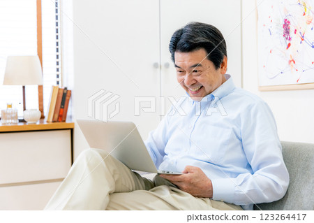 Senior man operating a smartphone and a computer 123264417