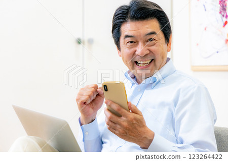 Senior man operating a smartphone and a computer Senior man operating a smartphone and a computer 123264422