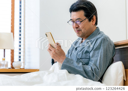 戴眼鏡的中年男子在床上使用智慧型手機 123264426