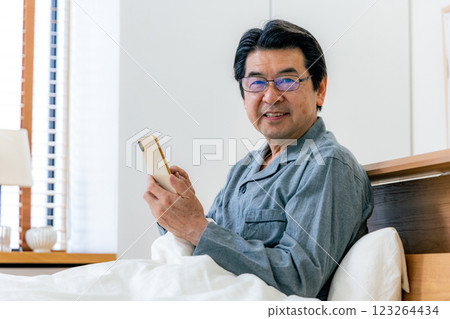 戴眼鏡的中年男子在床上使用智慧型手機 123264434