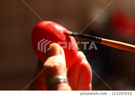 A woman's hand paints an Easter egg. Preparing Easter decorations on Multicolor background. A woman's hand paints an Easter egg. Preparing Easter decorations on Multicolor background. 123265018
