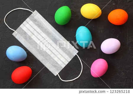 Medical protective face mask and colorful easter eggs isolated on black background. Concept of Easter holiday during the global pandemic coronavirus. Flat lay, top view, copy space. 123265218