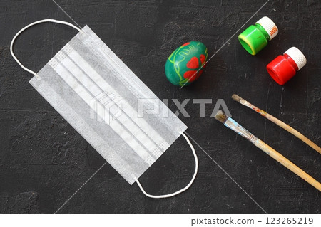 Medical protective face mask and colorful easter eggs isolated on black background. Concept of Easter holiday during the global pandemic coronavirus. Flat lay, top view, copy space. 123265219