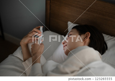 A woman using a smartphone in bed A woman using a smartphone in bed 123265555