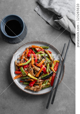 Stir-fry with vegetables and meat on dark background with chopsticks and soy sauce. Stir-fry with vegetables and meat on dark background with chopsticks and soy sauce. 123265610