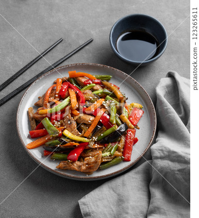 Stir-fry with vegetables and meat on dark background with chopsticks and soy sauce. Stir-fry with vegetables and meat on dark background with chopsticks and soy sauce. 123265611