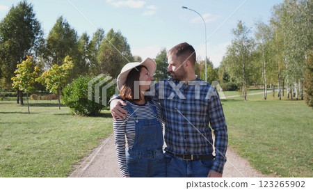 A joyful couple happily shares a special moment together while casually strolling hand in hand in a beautiful park 123265902