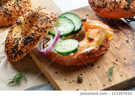 Assembling a lox bagel. Sandwich with smoked salmon and fresh vegetables 123265910