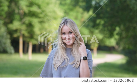 A cheerful and happy woman poses joyfully outdoors in a lush and vibrant green park, embodying pure joy and tranquility A cheerful and happy woman poses joyfully outdoors in a lush and vibrant green park, embodying pure joy and tranquility 123265968