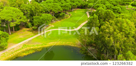 Aerial view of a golf course with a scenic pond, lush greenery, and winding paths Aerial view of a golf course with a scenic pond, lush greenery, and winding paths 123266382