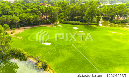 Aerial view of a golf course with sand traps, a pond, and lush greenery Aerial view of a golf course with sand traps, a pond, and lush greenery 123266385
