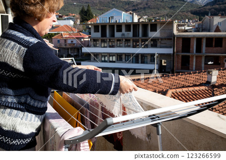 Woman hanging laundry on a terrace in the sunlight, energy conservation. Woman hanging laundry on a terrace in the sunlight, energy conservation. 123266599