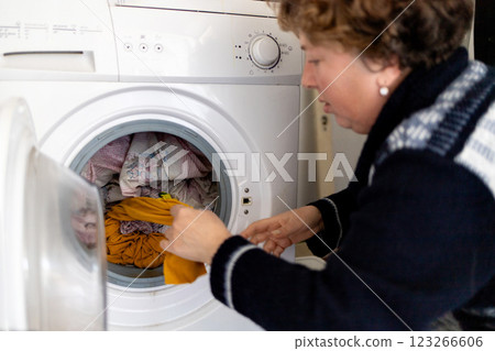 Mature woman taking clean laundry from washing machine, household chores. Mature woman taking clean laundry from washing machine, household chores. 123266606