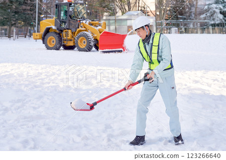Snow removal worker shoveling snow 123266640