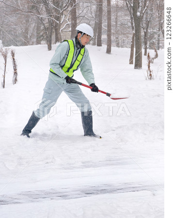 一名身穿工作服的男子正在鏟雪 123266648