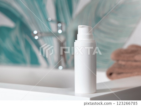 White cream bottle near brown folded towels on basin in tropical bathroom close up, cosmetic mockup 123266785