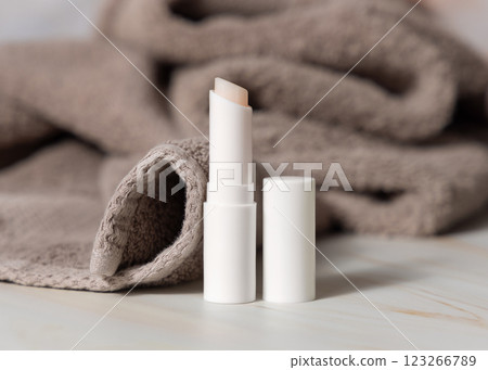 Opened white lip balm stick with a blank lid near brown bath towel closeup, herbal cosmetic mockup 123266789