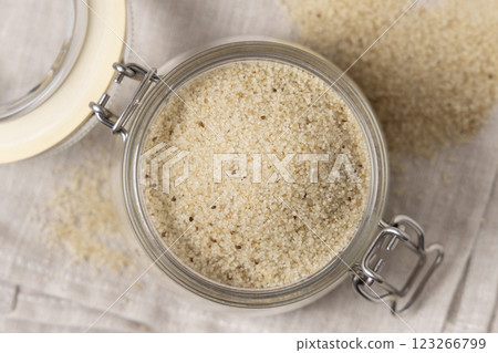 Jar of raw uncooked fonio seeds on gray napkin top view. African pseudocereal. Healthy food concept 123266799