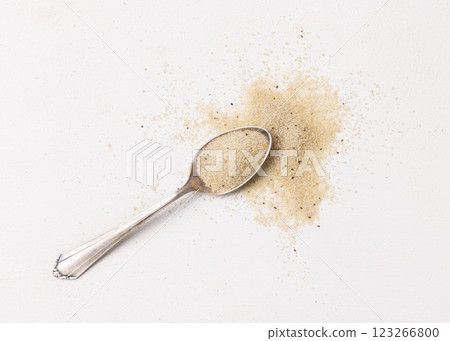 Raw uncooked fonio seeds in a metal spoon on white table, top view. African ancient pseudocereal 123266800