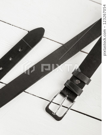 Black leather belt on a white wooden background. 123267054