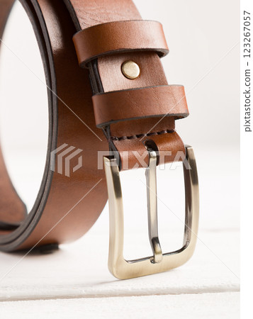 Brown leather belt on a white wooden background. Brown leather belt on a white wooden background. 123267057