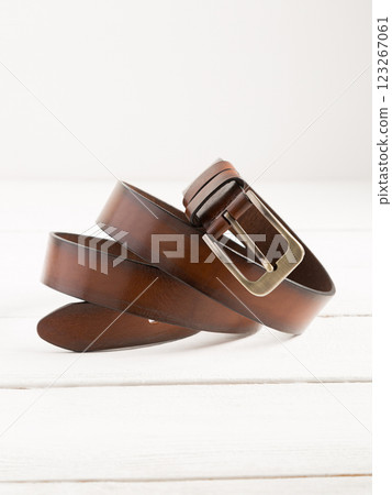 Brown leather belt on a white wooden background. 123267061