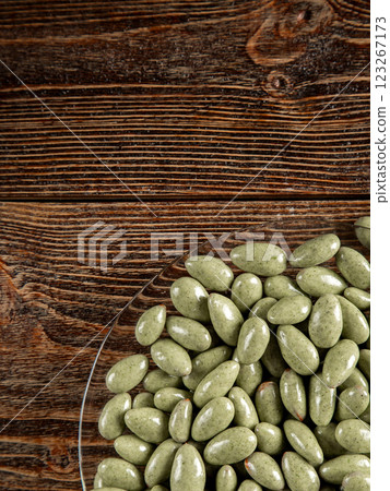 Green chocolates on a brown wooden background. Sweets in a glass plate. 123267173