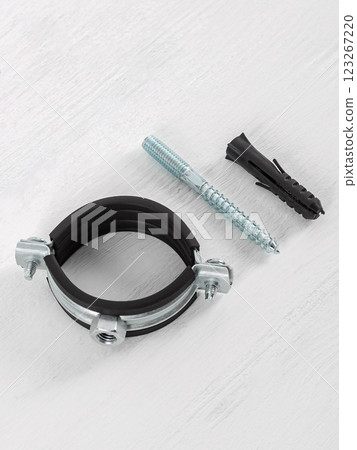 Clamp with fasteners on a white wooden background. Pipe holder. 123267220
