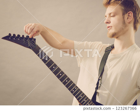 Man adjusting electric guitar Man adjusting electric guitar 123267366