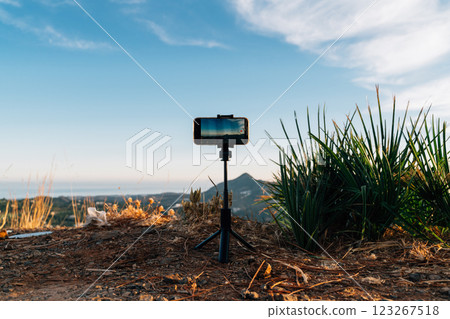 Smartphone on a tripod set up against a scenic backdrop of Andalusian hills at sunset in Malaga 123267518