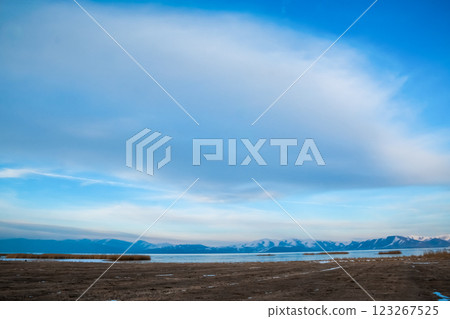Big cloud in the blue sky. Beautiful winter landscape with lake and mountains. Frozen lake and snowy mountains 123267525
