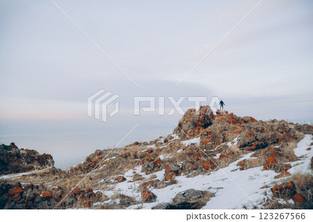 A man stands on the top of a cliff. A traveler stands on the top of a mountain and looks at the sea. Beautiful documentary landscape. Beautiful nature with a rocky mountain and a lake	 123267566