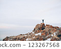 A man stands on the top of a cliff. A traveler stands on the top of a mountain and looks at the sea. Beautiful documentary landscape. Beautiful nature with a rocky mountain and a lake	 123267568