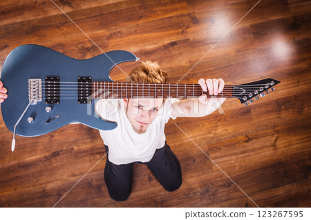 Proud man raising his electric guitar Proud man raising his electric guitar 123267595