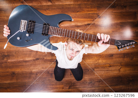 Proud man raising his electric guitar 123267596
