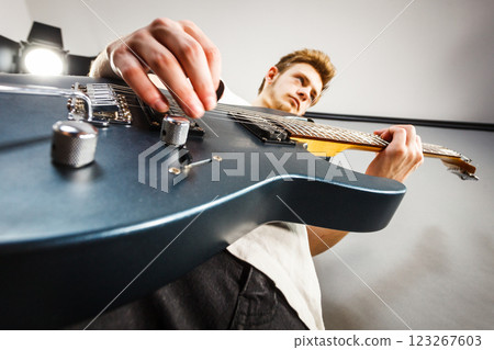 Young man is playing electric guitar 123267603
