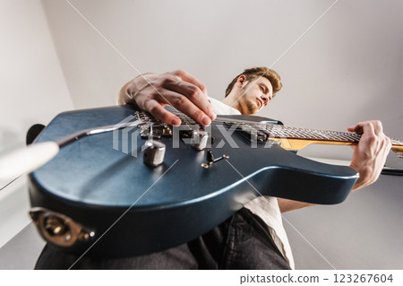 Young man playing electric guitar 123267604
