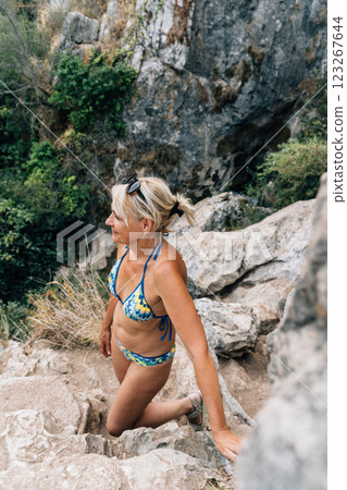 A woman in a patterned bikini climbing rocky terrain near the Cueva del Gato cave, enjoying an 123267644