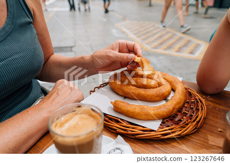 Hands serving freshly made churros alongside coffee at an outdoor cafe in Ronda, Spain, reflecting 123267646
