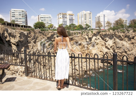 Woman in summer dress admiring coastal cliffside view Woman in summer dress admiring coastal cliffside view 123267722