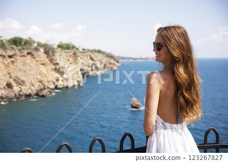 Smiling woman in summer dress enjoying ocean view  123267827
